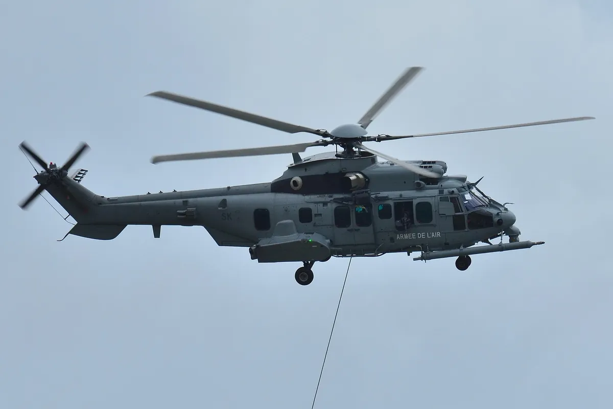 Hélicoptère Caracal de l'armée de l'Air posé sur un parking d'aérodrome, portes ouvertes
