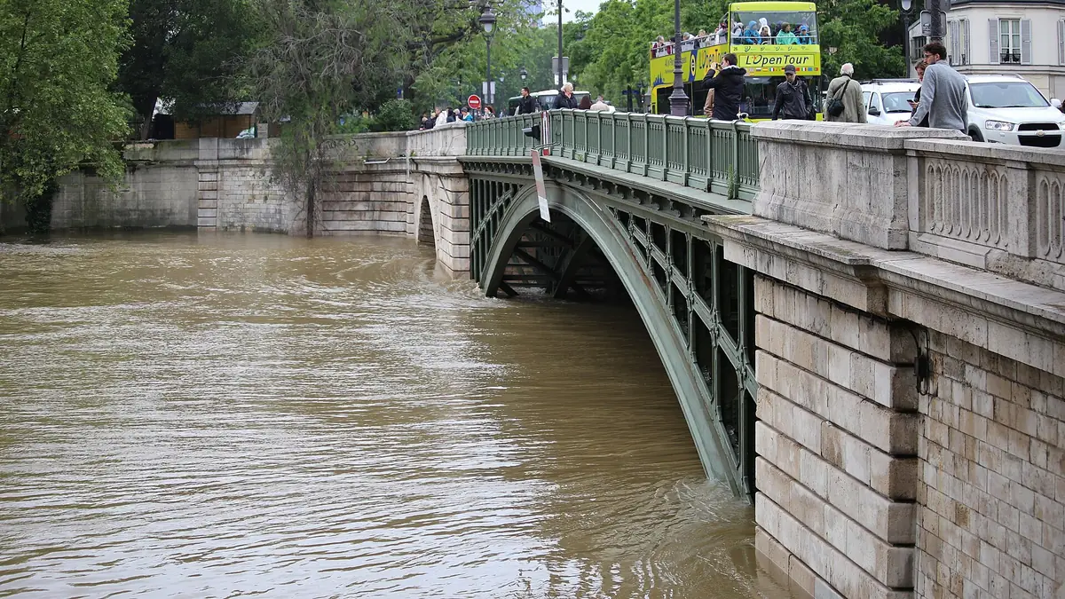 Pont métallique au ras d'une Seine boueuse et gonflée qui recouvre les berges