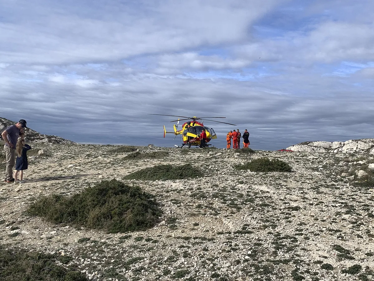 Hélicoptère de la Sécurité civile posé sur un terrain rocailleux, équipage en orange à côté